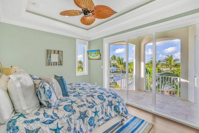 bedroom featuring a tray ceiling, access to outside, ornamental molding, and light hardwood / wood-style floors