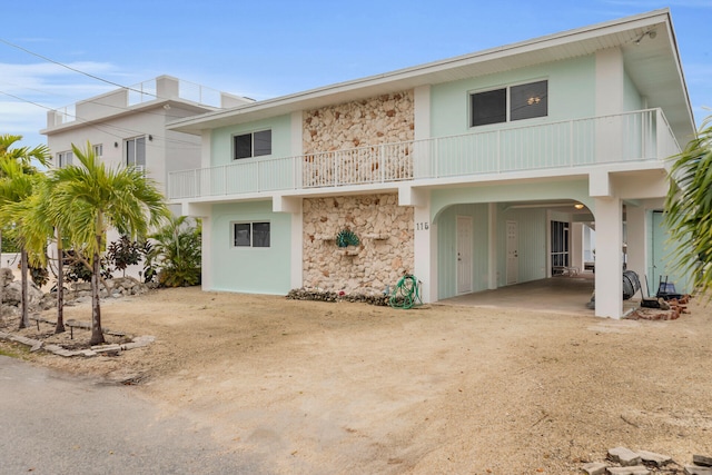 115 Primrose Ln, Long Key, FL 33001 - view of front of house featuring stone siding, a carport, a balcony, and stucco siding