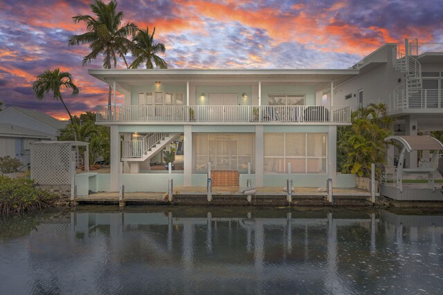 back house at dusk with a balcony and a water view