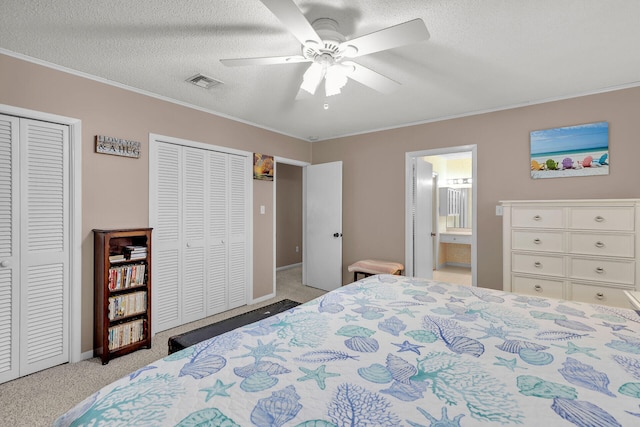 carpeted bedroom featuring multiple closets, crown molding, ceiling fan, and a textured ceiling