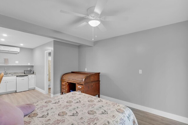 bedroom featuring sink, an AC wall unit, and light wood-type flooring