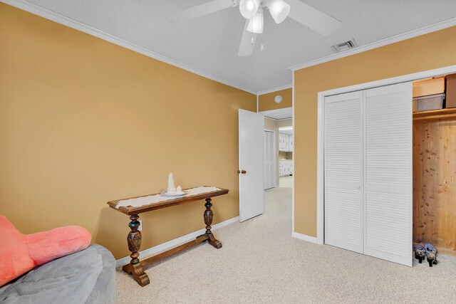 sitting room featuring ceiling fan, ornamental molding, and carpet flooring