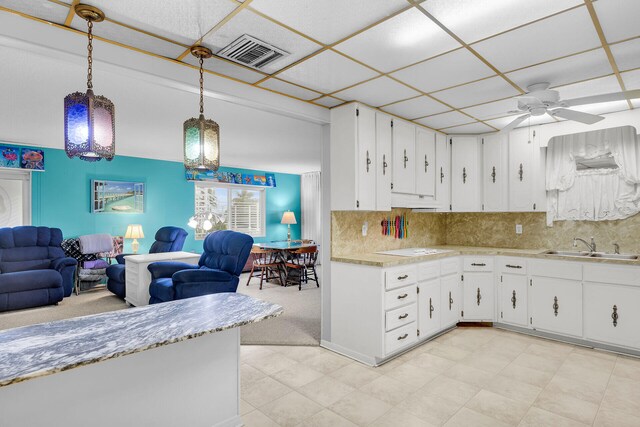 kitchen with hanging light fixtures, white cabinetry, and sink