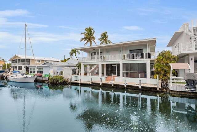 back of property featuring a sunroom, a balcony, and a water view