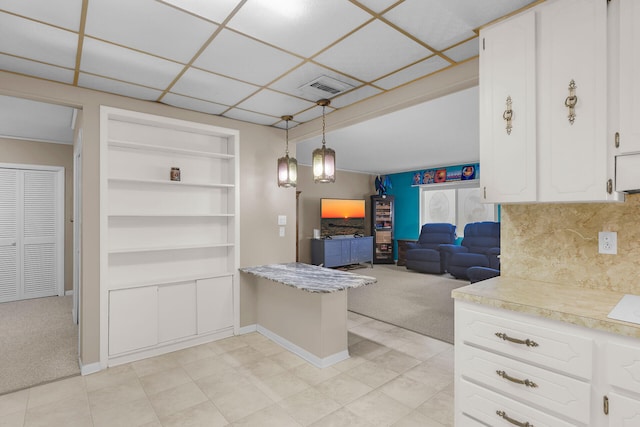 kitchen with light carpet, hanging light fixtures, and white cabinets