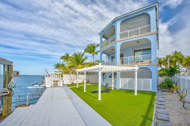 exterior space featuring a balcony, a water view, and a lawn