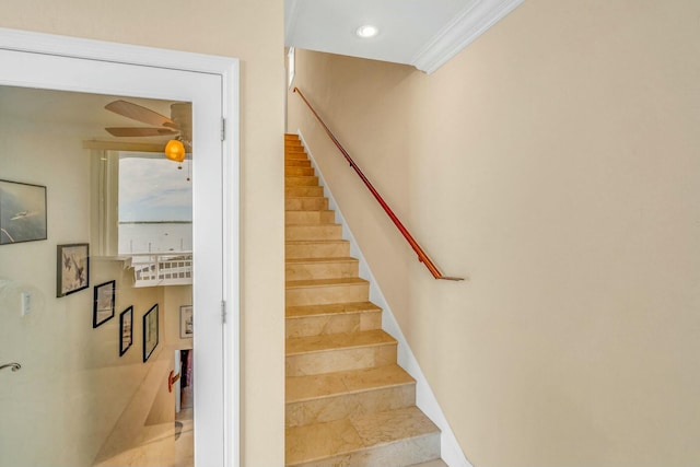 stairs featuring crown molding and ceiling fan