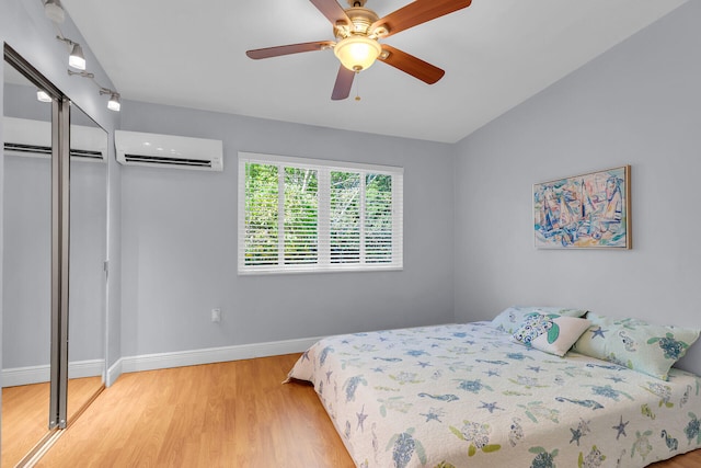 bedroom with a closet, ceiling fan, a wall unit AC, and light hardwood / wood-style flooring