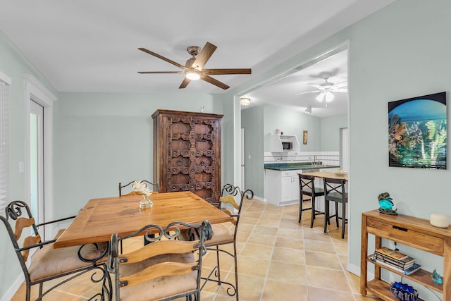 tiled dining area featuring ceiling fan and sink