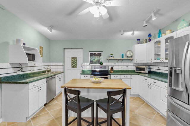 kitchen featuring tasteful backsplash, light tile patterned floors, stainless steel appliances, and white cabinets