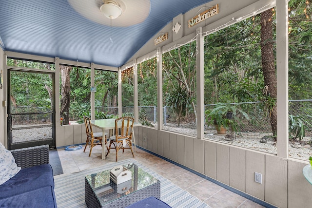 unfurnished sunroom with ceiling fan, plenty of natural light, and vaulted ceiling