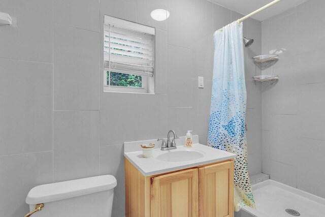 bathroom with a shower with curtain, vanity, toilet, and tile walls