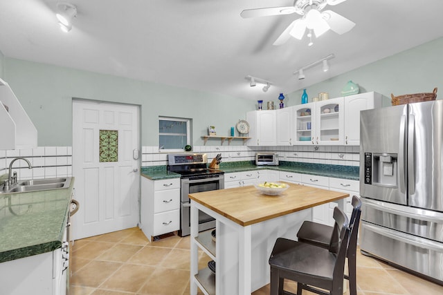 kitchen with white cabinetry, stainless steel appliances, light tile patterned flooring, and sink