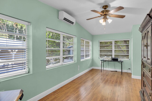 unfurnished office featuring a wall mounted air conditioner, a wealth of natural light, vaulted ceiling, and light wood-type flooring