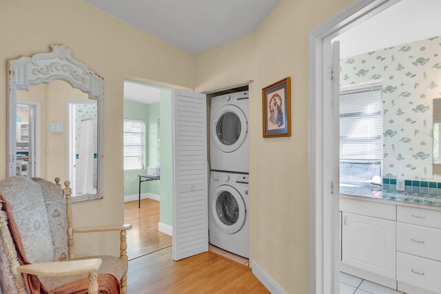 washroom with stacked washing maching and dryer and light hardwood / wood-style flooring