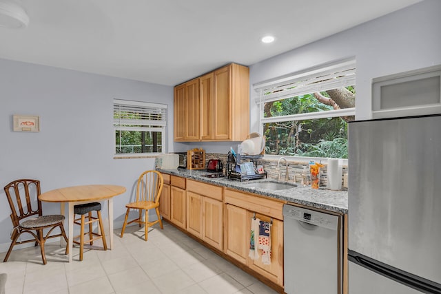 kitchen with sink, stainless steel appliances, dark stone counters, and light brown cabinets