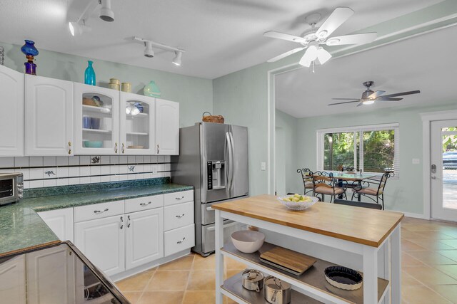 kitchen featuring white cabinetry, backsplash, light tile patterned floors, ceiling fan, and stainless steel refrigerator with ice dispenser