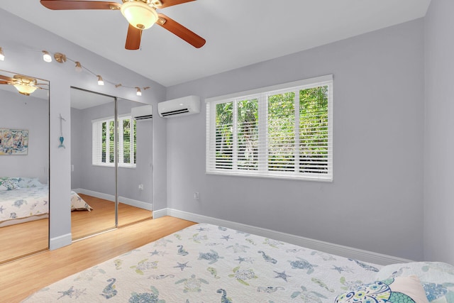 bedroom featuring multiple closets, lofted ceiling, hardwood / wood-style floors, and an AC wall unit