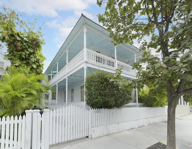 view of front of house featuring a balcony and a fenced front yard