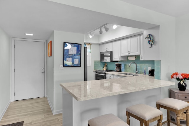 389 N Anglers Dr Unit 105, Marathon, FL 33050 - kitchen with appliances with stainless steel finishes, light stone counters, white cabinetry, tasteful backsplash, and light wood-type flooring