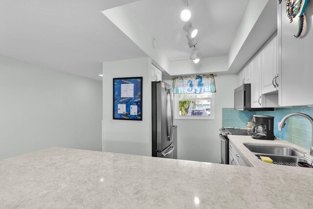389 N Anglers Dr Unit 105, Marathon, FL 33050 - kitchen featuring stainless steel appliances, rail lighting, backsplash, and white cabinets