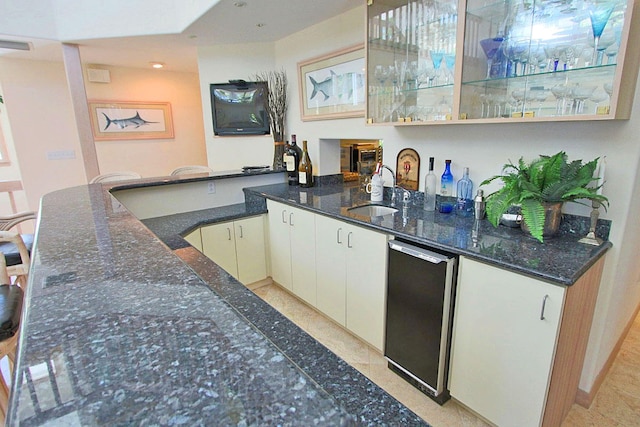 bar featuring sink, dark stone countertops, and white cabinets