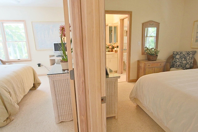 bedroom featuring ensuite bathroom and light carpet