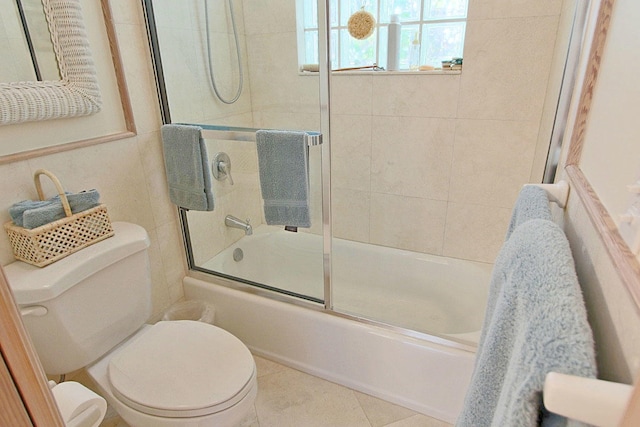 bathroom featuring toilet, tile patterned floors, and shower / bath combination with glass door