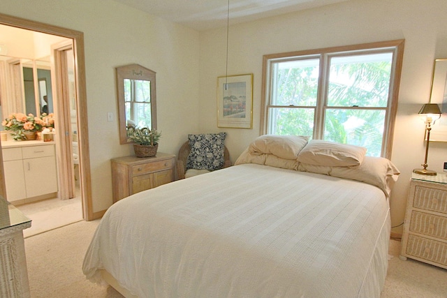 bedroom with light colored carpet and ensuite bath