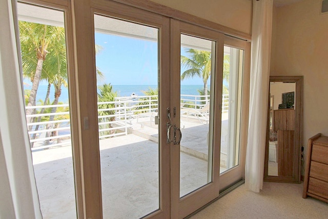 entryway with carpet flooring, plenty of natural light, french doors, and a water view