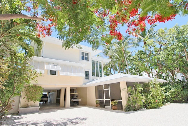 back of property featuring a sunroom and a carport