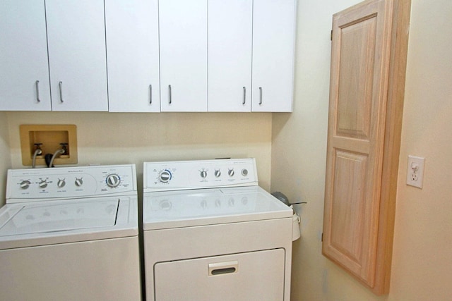 clothes washing area featuring washer and clothes dryer and cabinets