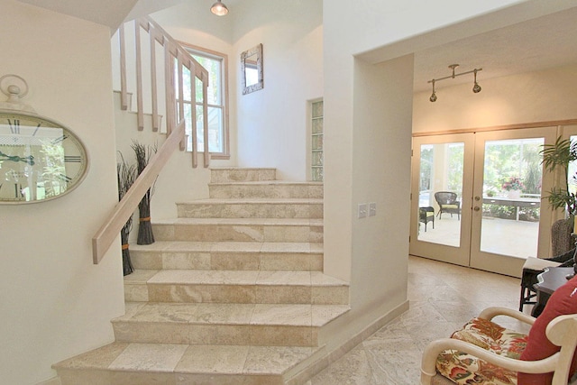 staircase featuring plenty of natural light, track lighting, and french doors