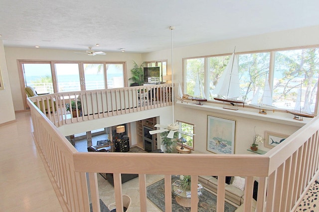 interior space with a water view, a textured ceiling, and ceiling fan