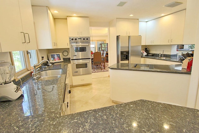 kitchen with white cabinetry, appliances with stainless steel finishes, sink, and dark stone countertops