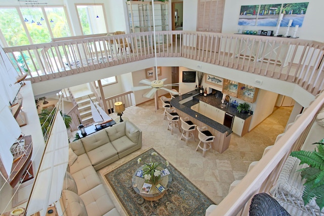 living room with ceiling fan and a towering ceiling