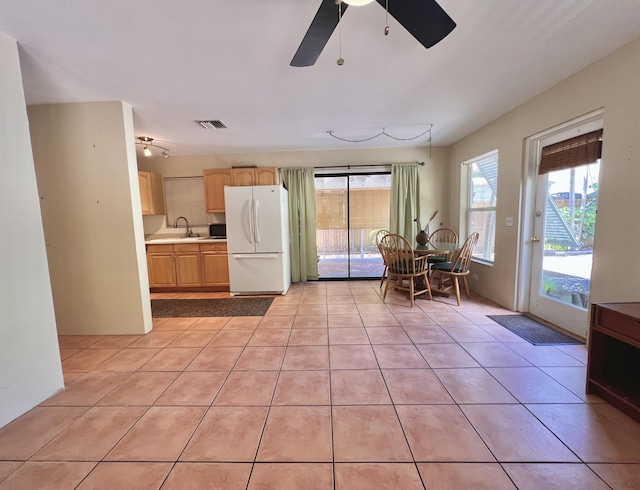 interior space featuring white fridge, sink, light tile patterned floors, and light brown cabinetry