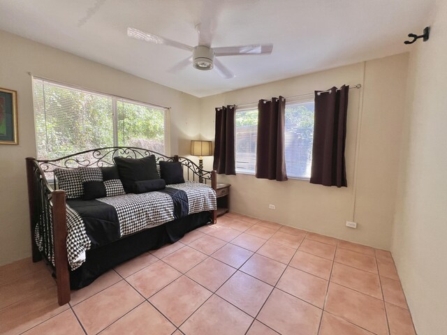 tiled bedroom featuring ceiling fan and multiple windows