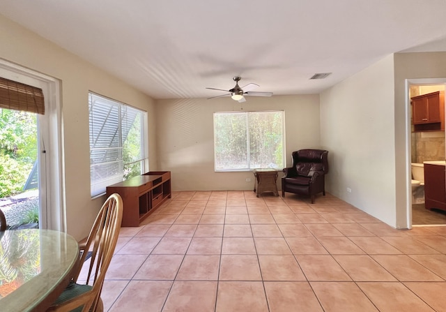 living area with light tile patterned floors and ceiling fan