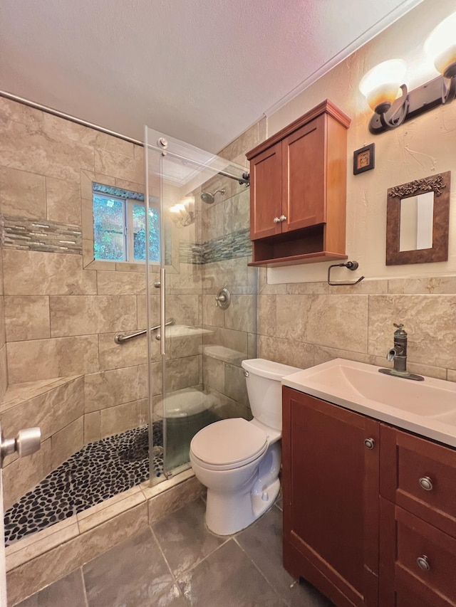 bathroom with tile walls, vanity, walk in shower, toilet, and a textured ceiling