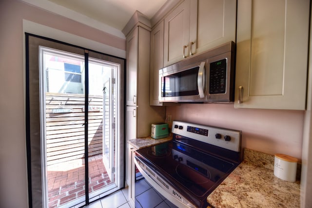 kitchen featuring light tile patterned floors, appliances with stainless steel finishes, and light stone counters