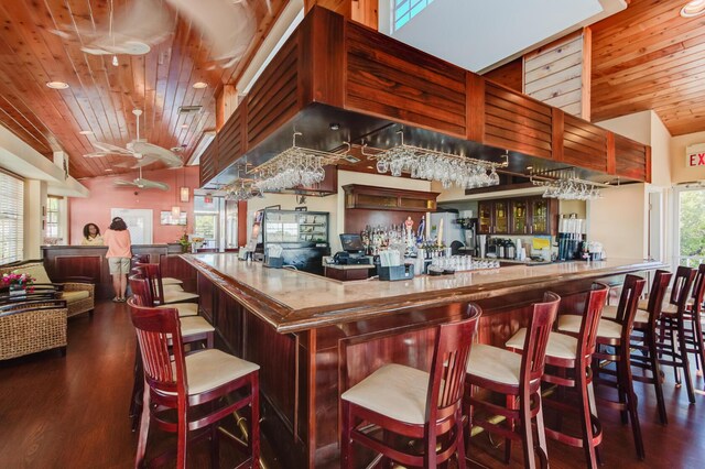 bar featuring a community bar, wooden ceiling, vaulted ceiling, and wood finished floors