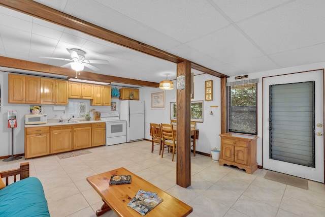 kitchen with a paneled ceiling, white appliances, a sink, light countertops, and hanging light fixtures