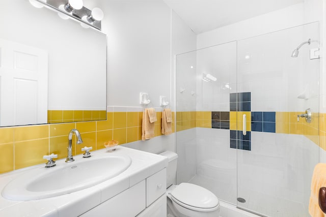 bathroom featuring vanity, a shower with shower door, tile walls, and toilet