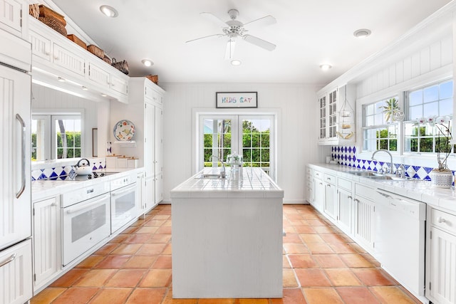 kitchen featuring an island with sink, sink, white cabinets, white appliances, and french doors