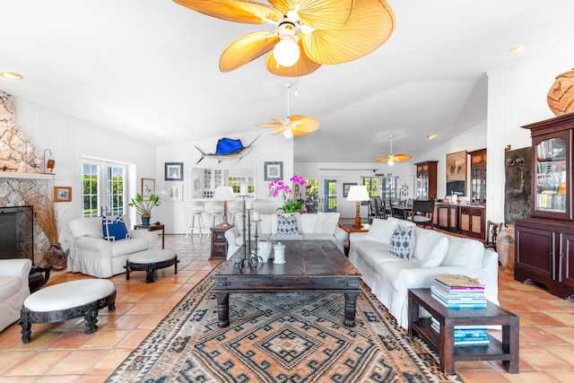 tiled living room with lofted ceiling, a stone fireplace, french doors, and ceiling fan