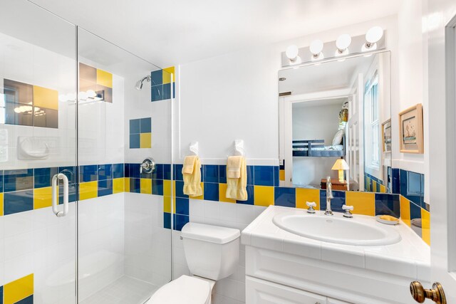 bathroom with tile walls, vanity, toilet, and walk in shower