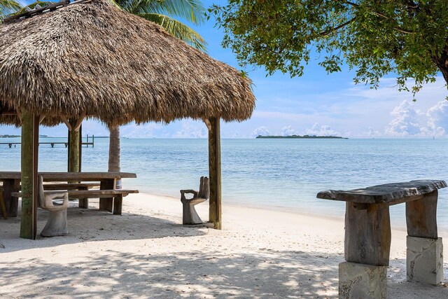 view of dock with a gazebo, a beach view, and a water view