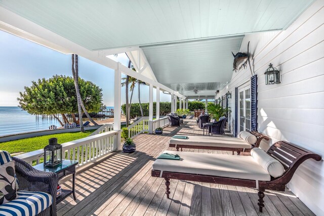 wooden terrace with a water view and ceiling fan