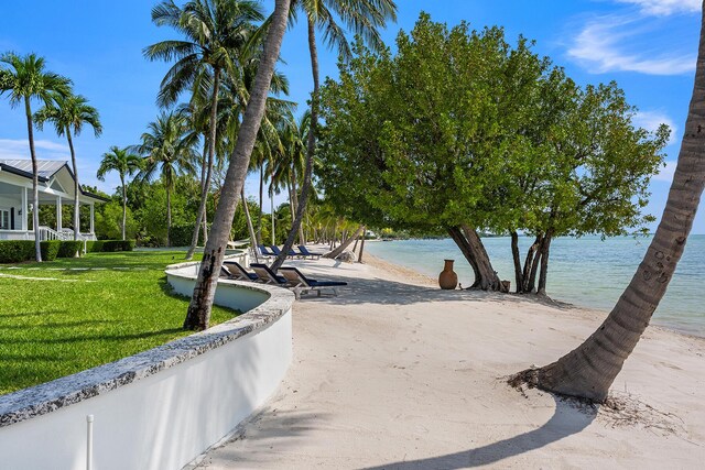 surrounding community with a lawn, a beach view, and a water view